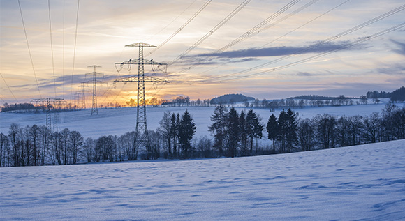 Winter landscape with power poles and sunset.