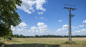Electricity pole in a field with blue sky.