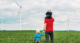 Family standing in a field looking at wind turbines.
