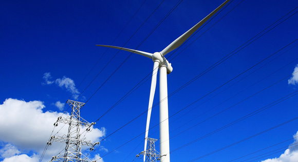 Wind turbine, powerlines and blue sky.