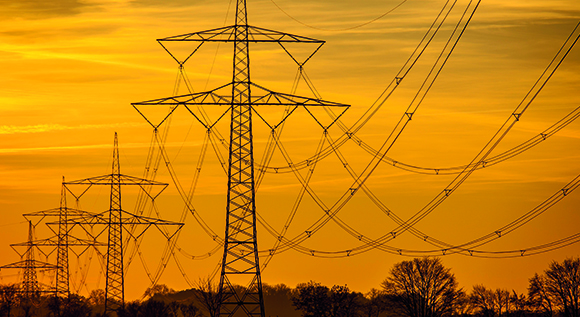 Strommasten und Stromleitungen im Sonnenuntergang
